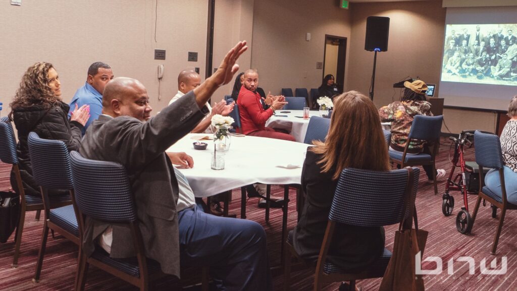Representative David Hackney raises his arm after being acknowledged at the Black Eco Chamber Mixer Event in Celebration of Black History Month.